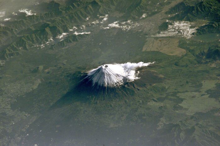 Aerial view of an iconic snow-capped mountain with surrounding landscape.
