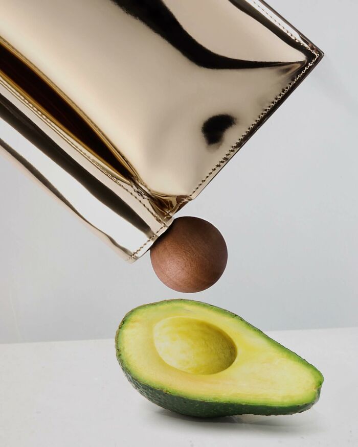 Avocado illusion by Dudi Ben Simon: sleek metallic object hovering above halved avocado with seed.