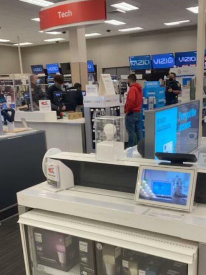 Customer in a tech store, browsing electronics with Vizio displays in the background.