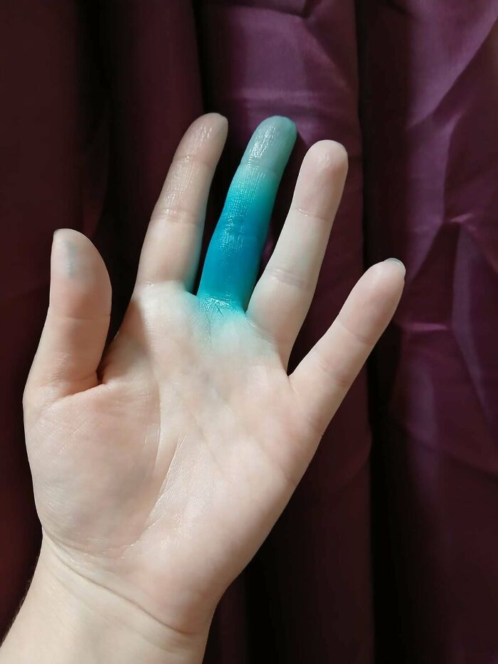 Hand with blue finger paint against a purple background, highlighting mundane moments.