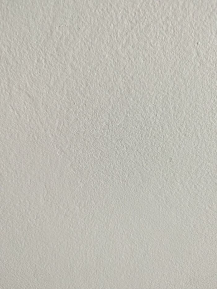 Unremarkable plain wall texture, mainly in white, emphasizing simplicity and minimalism.