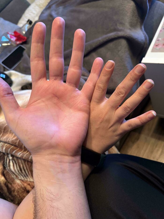 "Two hands held up against a background, showcasing a size comparison in an ordinary, uninteresting setting."