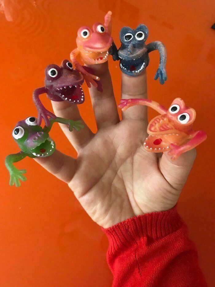 Colorful plastic finger puppets on a hand, reminiscent of 1980s toys.