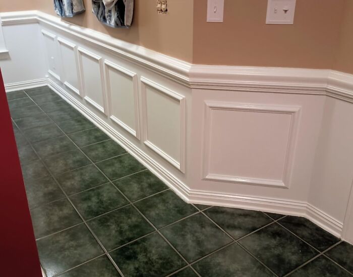DIY home project featuring white wainscoting with green-tiled floor and beige walls.