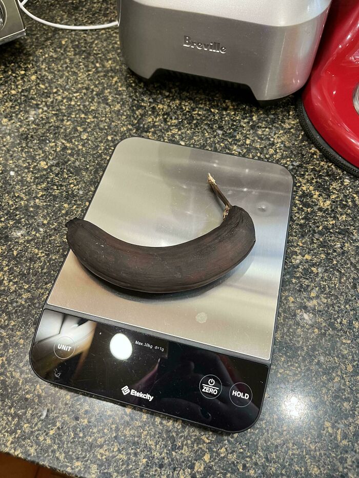 A blackened banana on a digital kitchen scale, nothing interesting in sight.