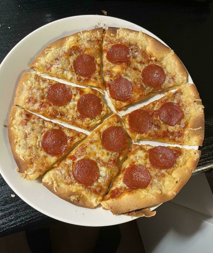 A plain pepperoni pizza cut into eight slices on a white plate.