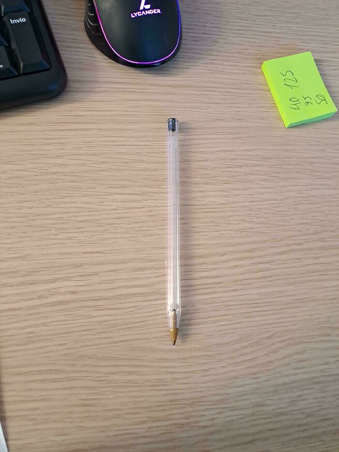 Unremarkable pen on a desk with a mouse, keyboard, and sticky notes.