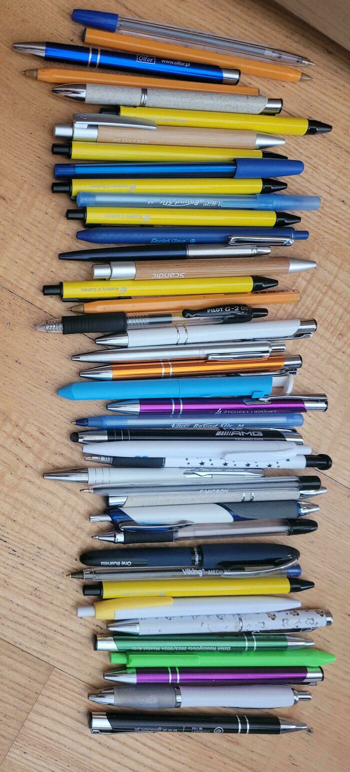 Assorted pens arranged on a wooden surface, showcasing various colors and styles.