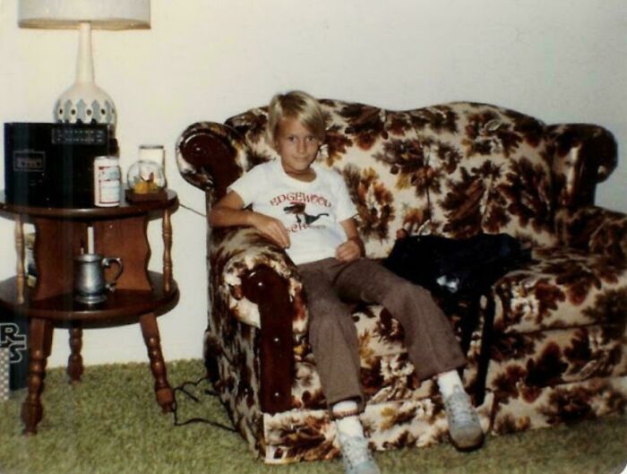 Child sitting on a floral 80s couch with vintage decor, capturing the essence of the 1980s vibe.