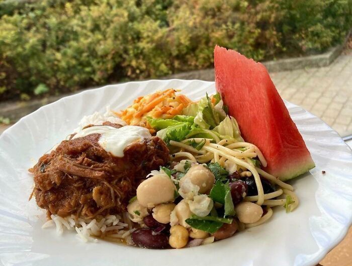 Plato variado con detalles ingeniosos de la vida cotidiana de diversos países: arroz, carne, ensalada y sandía.