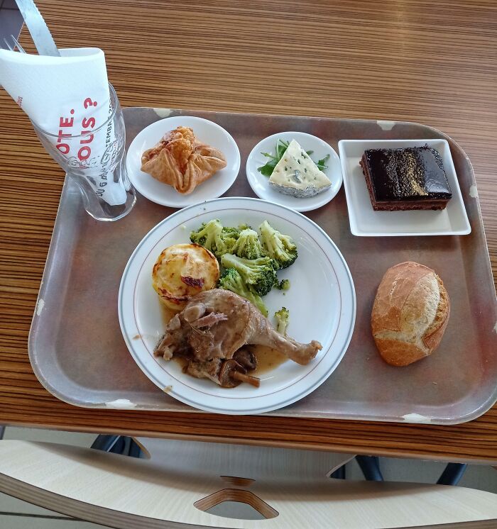 Bandeja con comida francesa: pato, brócoli, patata, queso, pastel y panecillo. Detalles ingeniosos culinarios globales.