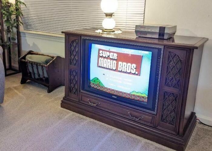 Vintage 1980s television setup featuring Super Mario Bros. and a classic gaming console in a retro living room.