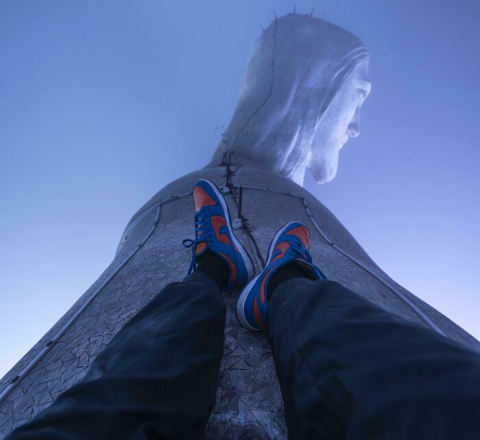 Reclining view of iconic place with person wearing blue and orange sneakers against a towering statue.