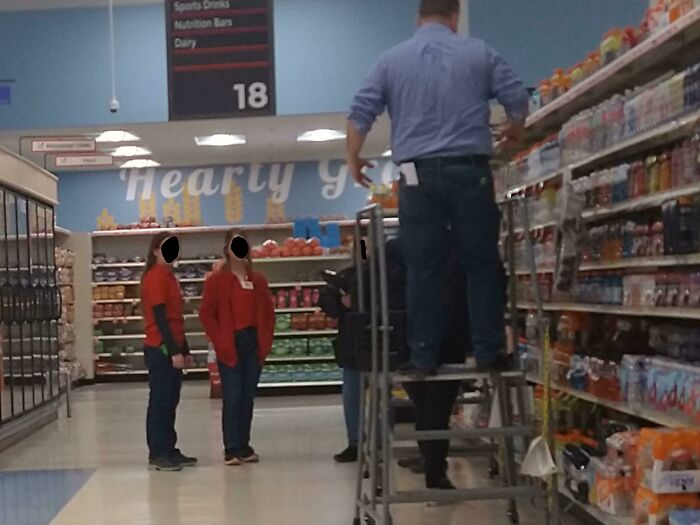 Workers in a grocery aisle with one on a ladder, highlighting challenging colleagues, store aisle 18 in the background.