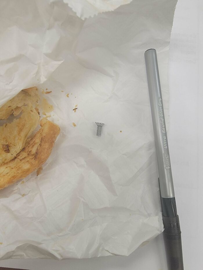 Croissant with a s***w nearby on paper, next to a pen, illustrating someone's worst day at work.