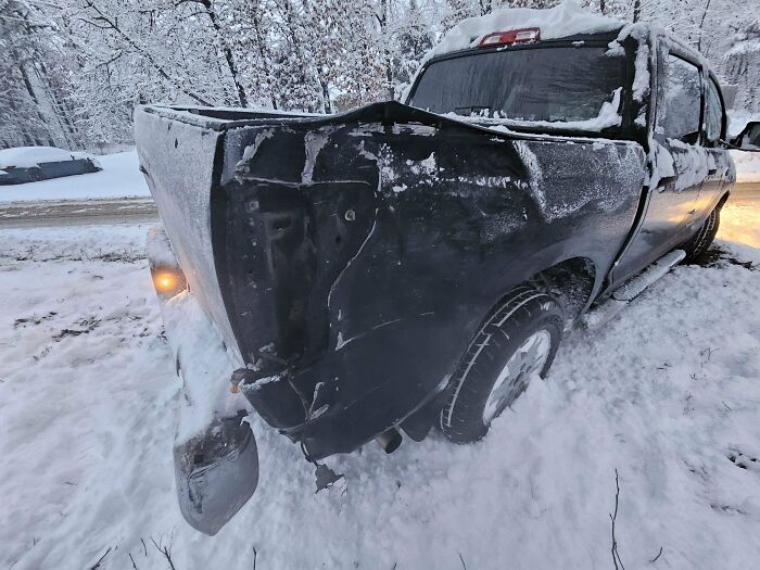 Damaged truck in snowy landscape, rear end severely crushed, highlighting a worst day at work scenario.