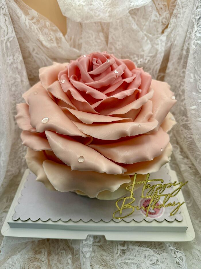 Pink rose-shaped cake with delicate petals and water droplet decorations, showcasing incredible bakes and artistic detail.