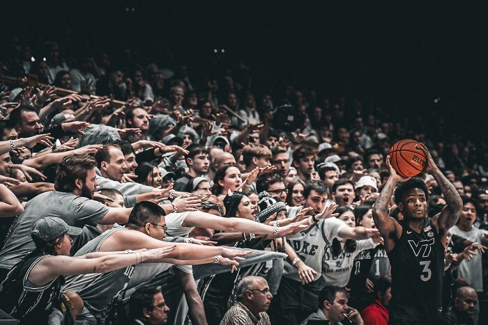 Crowd reaching out toward basketball player holding ball, resembling a scene captured like a Renaissance masterpiece moment.