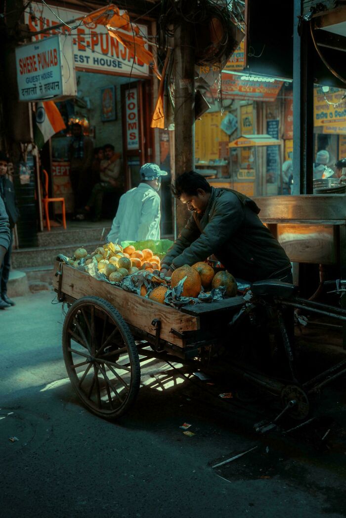 Street vendor arranging fruits on a cart in warm light, captured with the look of a Renaissance masterpiece painting.