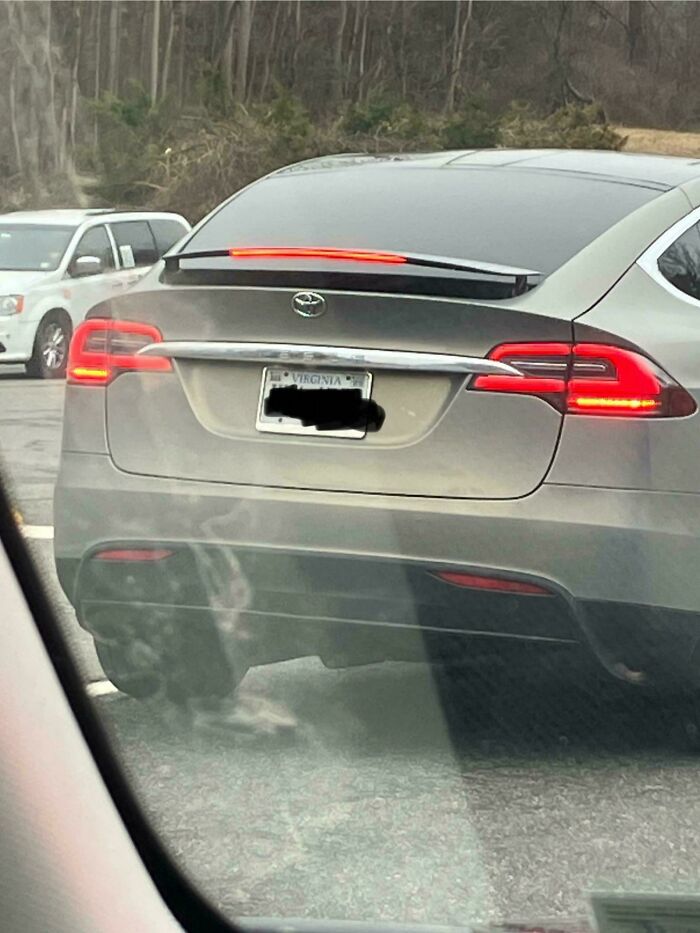 Rear view of a Tesla car with a Toyota emblem attached, showcasing a failed attempt to disguise the brand.