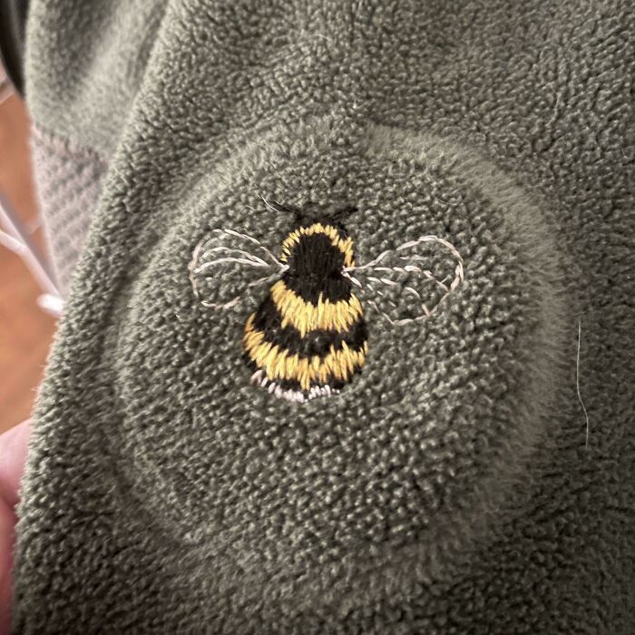 Embroidered bee design on textured fabric showcasing beautiful and incredible embroidery skills in close-up detail.