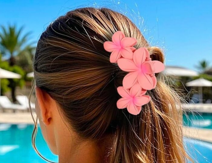Hair styled with pink flower clip by a pool, essential spring accessory.