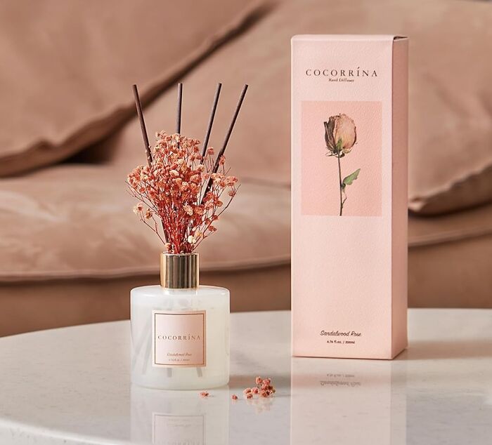 Fragrant diffuser on a marble table, decorated with dried flowers and a matching pink box, essential for spring refreshment.