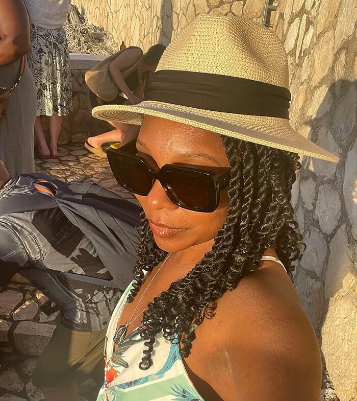 Woman enjoying spring sun in a straw hat and sunglasses, showcasing essential style for the season.