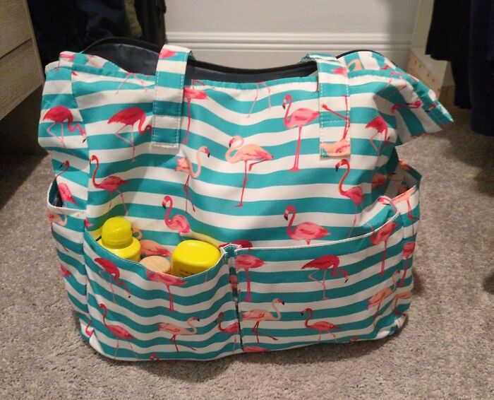 Flamingo-patterned tote bag containing various items on a carpeted floor, highlighting essential spring accessories.