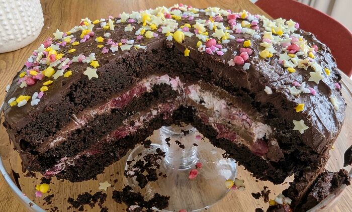 Chocolate cake with colorful star-shaped and heart sprinkles on a wooden table, a sweet treat for wholesome parenting moments