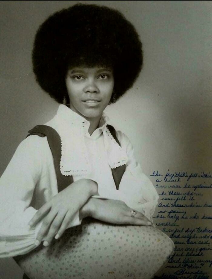 Black and white portrait of a young woman with afro hairstyle, showcasing candid glimpses into the past in vintage style.