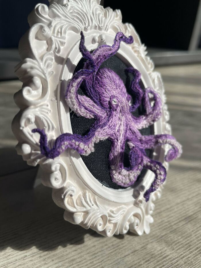 Intricate purple octopus embroidery showcased in a detailed white ornate frame highlighting embroidery skills.