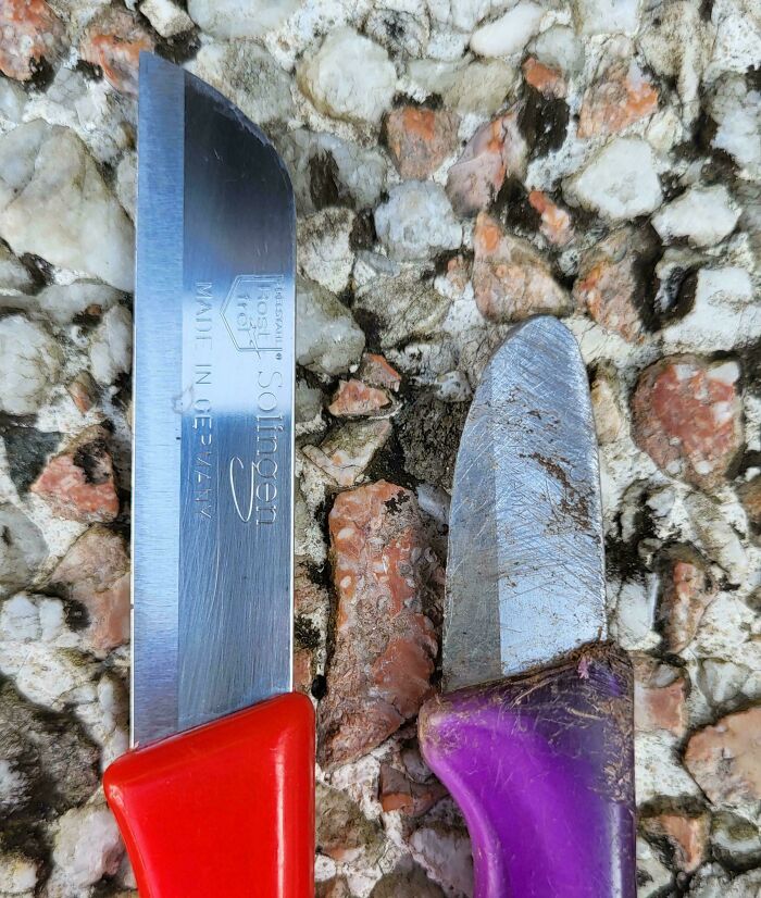 Dos cuchillos, uno nuevo y otro desgastado por el tiempo, sobre un fondo de piedras pequeñas.