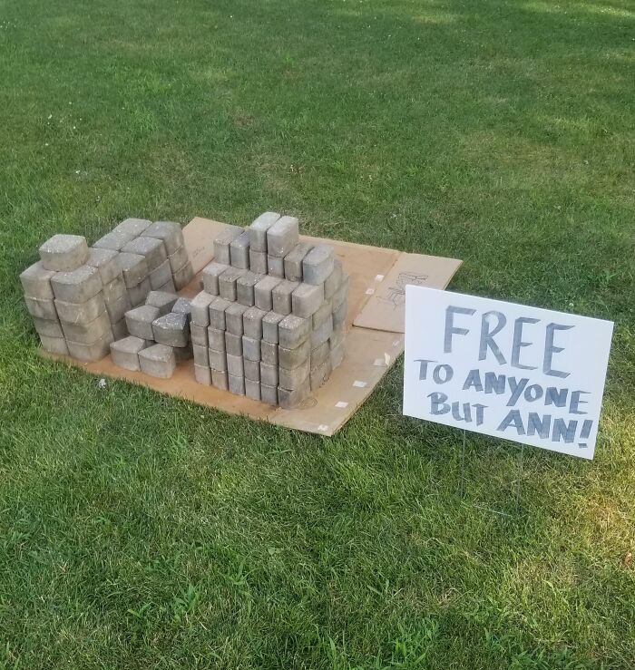 Bricks on grass with a sign, "Free to anyone but Ann," showcasing a funny passive-aggressive encounter.