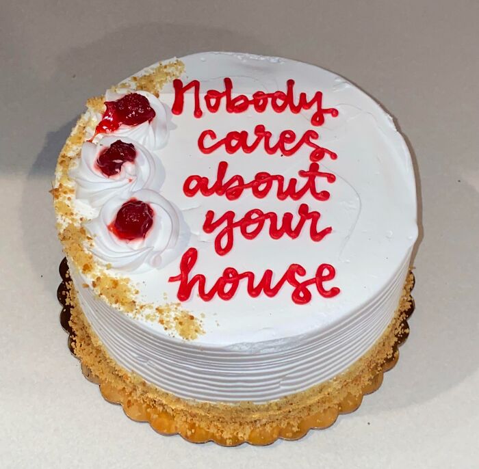 Passive-aggressive cake with red icing message, "Nobody cares about your house," topped with whipped cream and cherries.