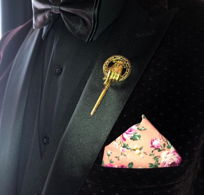 Decorative movie prop pin on a suit lapel with floral pocket square.