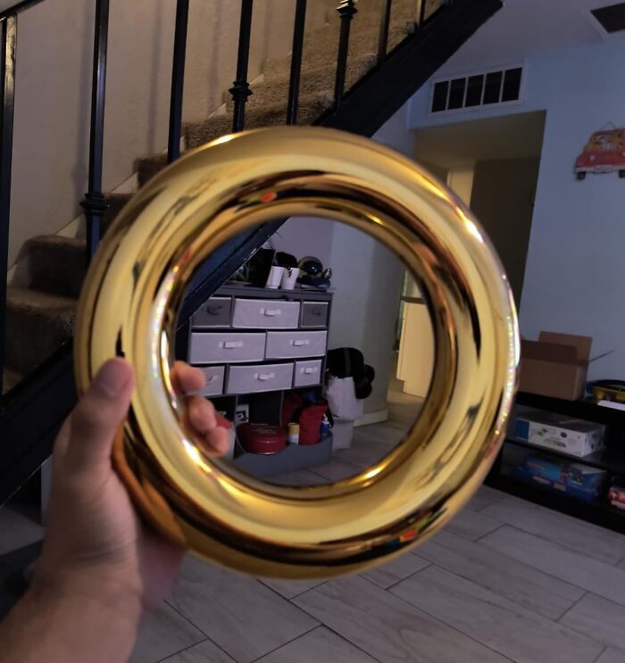 A hand holding a shiny gold movie prop in a living room setting.