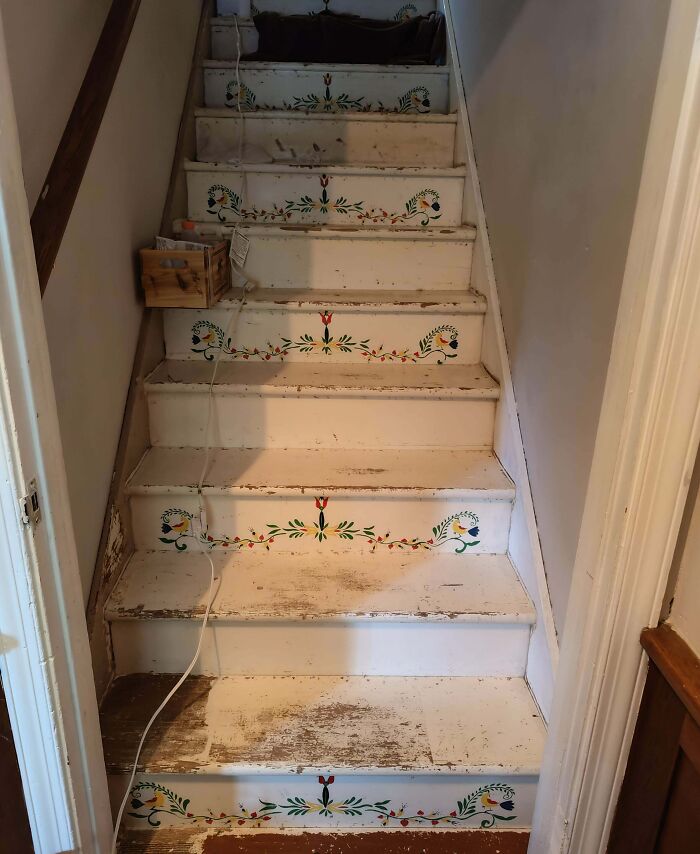 Old house staircase with vintage floral designs on worn steps.