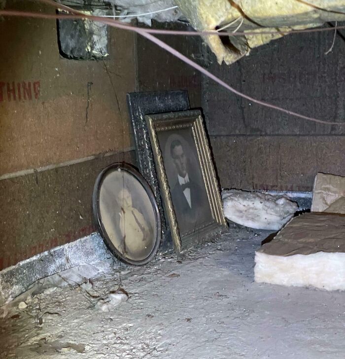 Old artifacts found in a dusty attic, featuring framed vintage portraits leaning against a wall.