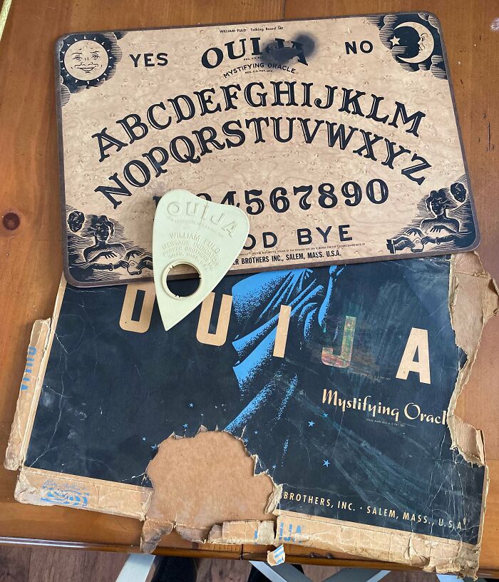 Vintage Ouija board artifact with planchette and box on a wooden table.
