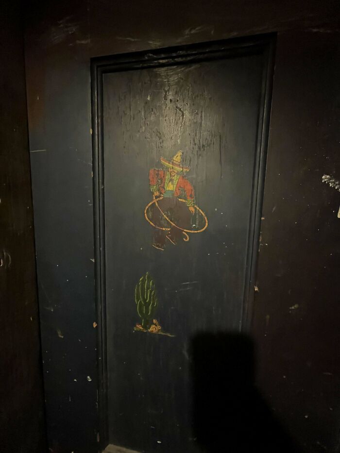 Old painted door with cowboy and cactus artwork, found in an old house.