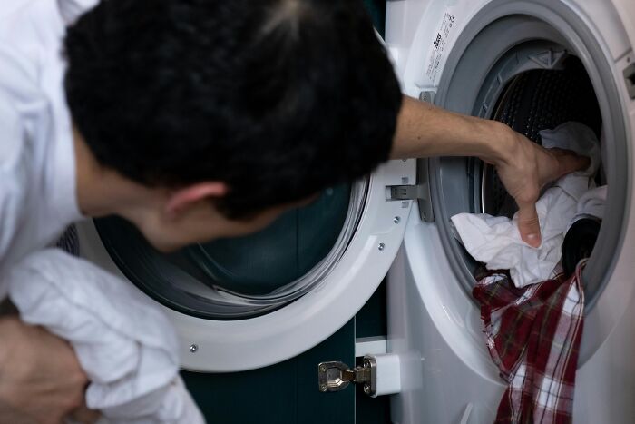 Person using a washing machine to load clothes, demonstrating simple approaches for better daily life.