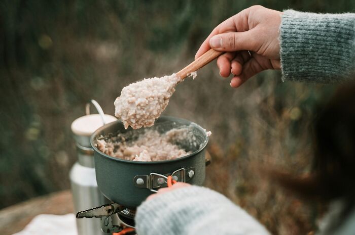 Preparing oatmeal in a pot outdoors, highlighting simple approaches for a better life.