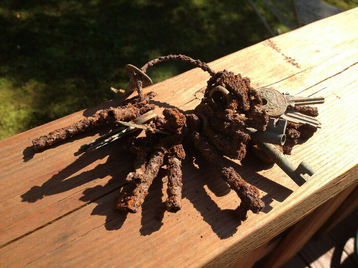 Rusted set of old keys on a wooden surface, discovered in a house, showcasing interesting artifacts from the past.