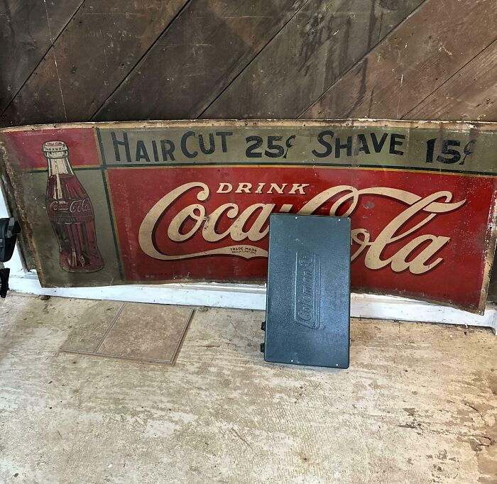 Vintage Coca-Cola sign discovered in an old house, advertising haircuts and shaves at 25¢ and 15¢ respectively.