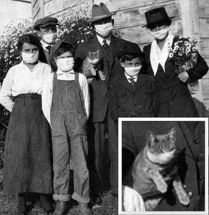 Vintage photo of a family wearing masks, including a cat, posing outdoors, capturing a positively ridiculous moment.