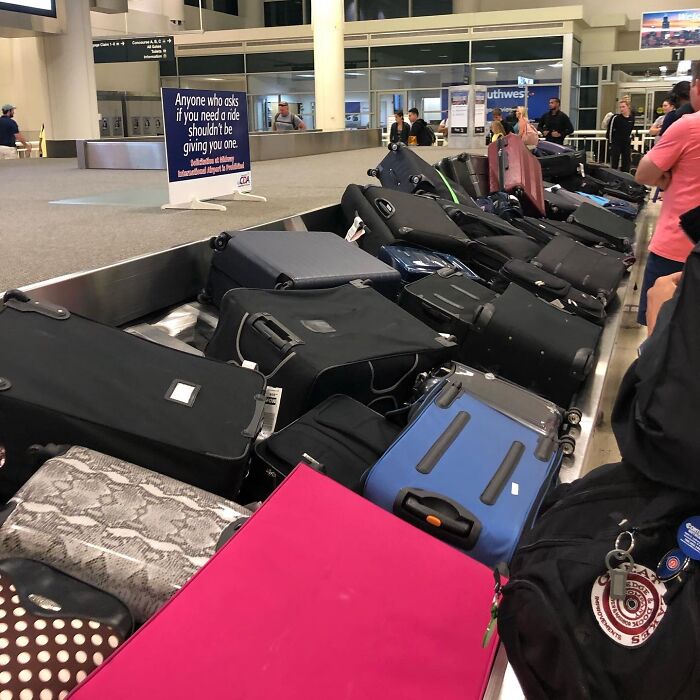 Baggage fail at airport carousel, luggage piled up chaotically, causing passenger frustration and inconvenience.