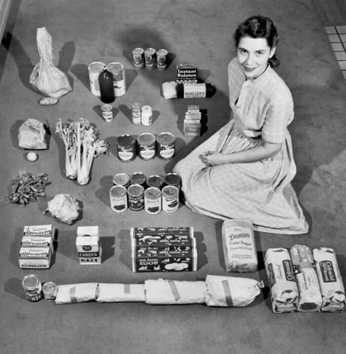 Woman with vintage groceries lined up, showcasing ridiculous items from the past.