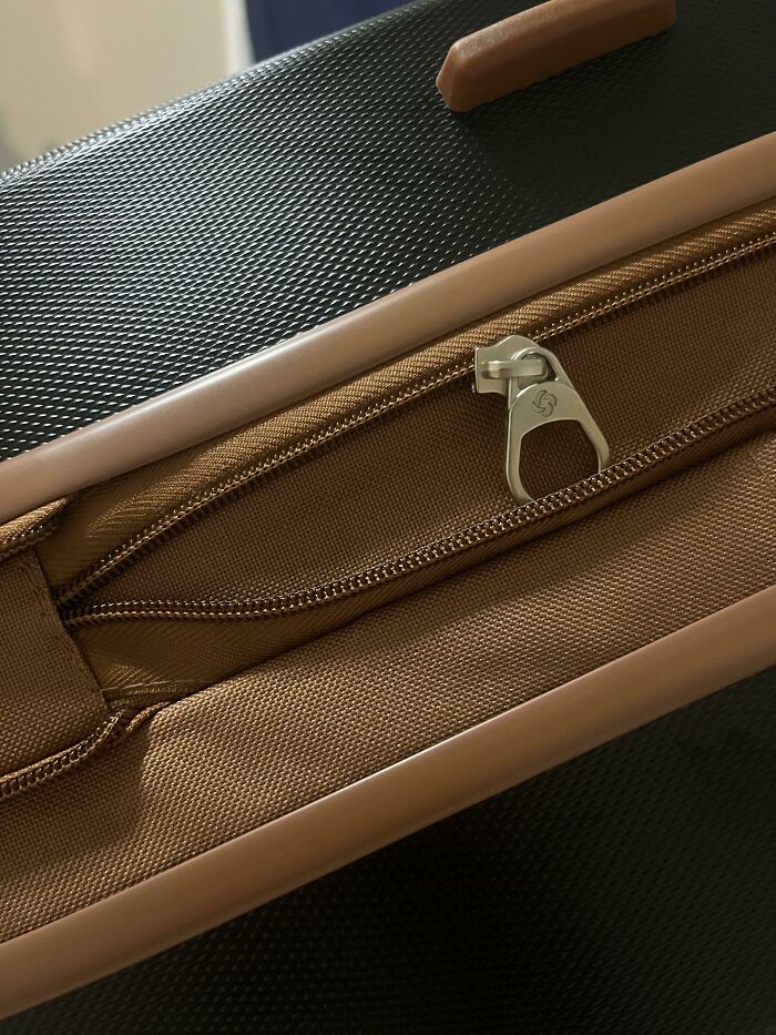 Airline baggage mishap with a torn zipper on a suitcase.