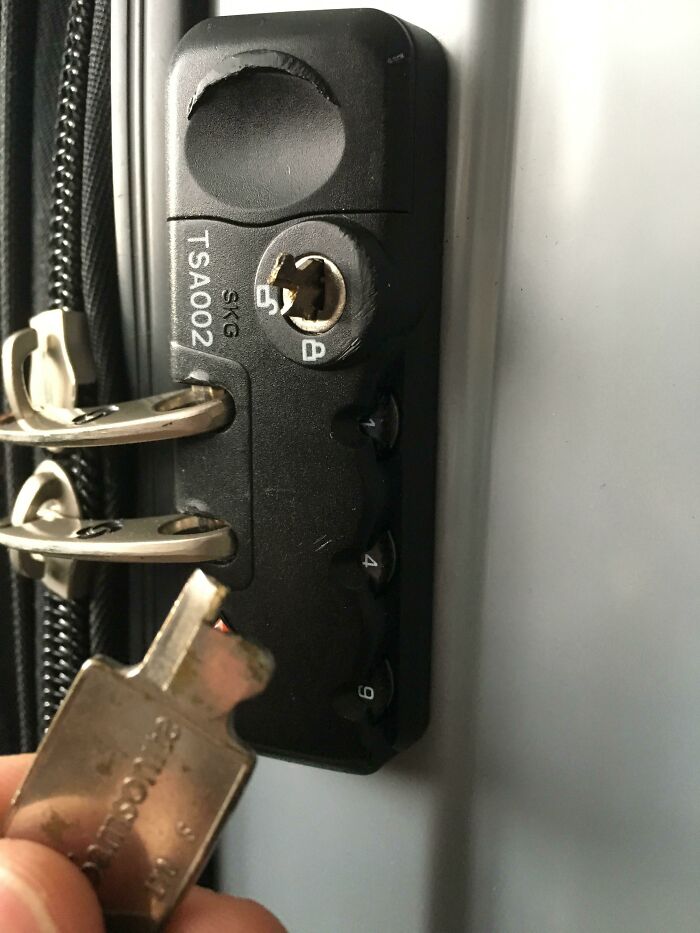 Baggage fail with key stuck in a damaged TSA lock on a suitcase.